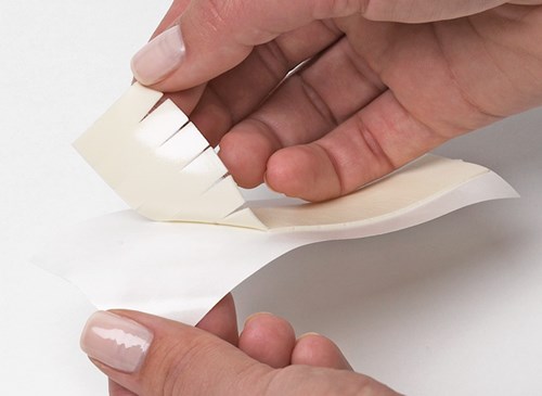 Hands removing TenderTouch from backing, showing flexibility of product