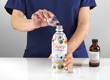 Tech pouring oral iodinated contrast into Breeza bottle